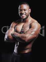 Confidence is earned. Studio portrait of a fit young man posing against a black background.