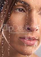 Experiencing a refreshing note to her day. Studio shot of a beautiful young woman taking a shower against a grey background.