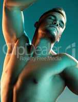 Movement is the song of the body. Studio shot of a handsome young man posing against a blue background.
