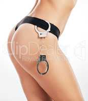 Time for a little role play. an unrecognizable woman posing with handcuffs in her under against a grey background in studio.