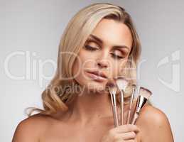 Makeup or no makeup, Im always the same person inside. Studio portrait of a beautiful young woman holding a set of makeup brushes against a grey background.