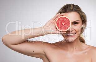 Beauty itself is but the sensible image of the Infinite. Studio shot of a beautiful young woman posing with a grape fruit against a grey background.