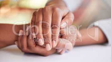 Everyone needs a little support. two unrecognizable people holding hands in comfort at a table at home.