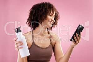 Keeping track of my fitness. an attractive young female athlete checking her text messages in studio against a pink background.