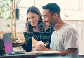 Happy, smiling, cheerful entrepreneurs browsing the internet on a laptop inside a coffee shop. Two latino bloggers sharing ideas and laughing while posting online content inside a quiet restaurant