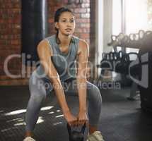 Make sure your form is right or youll get hurt. a sporty young woman exercising with a kettlebell in a gym.