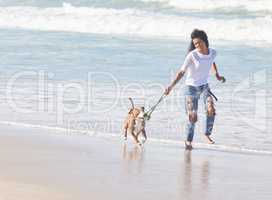 The best things in life are furry. a woman playing with her pit bull at the beach.