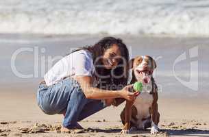 Apparently patience gets you treats. a woman playing with her pit bull at the beach.