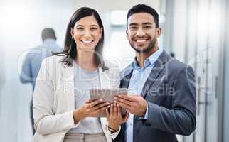 Big things have small beginnings. two businesspeople standing together and holding a digital tablet in an office.