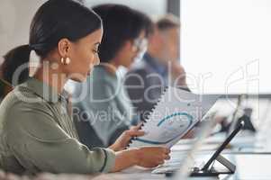 Analysing some plans to boost their sales. a young businesswoman going through paperwork while working alongside her colleagues in a call centre.