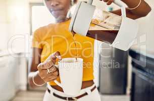 Hands of woman pouring coffee into a mug, standing inside a kitchen at home. French press with homemade, fresh, and delicious warm drink to start the morning or day with a brewed caffeine beverage