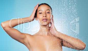 Skincare is a habit. an attractive young woman posing against a blue background while taking a shower.