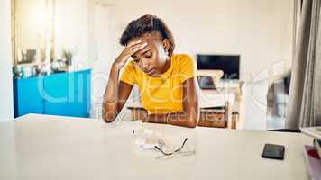 Stressed, tired and frustrated African student sitting in her room thinking about stressful problems. Depressed, anxious and exhausted female worried about sad news in her house.