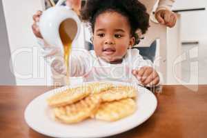 Something sweet for my sweet tooth. a little girl pouring honey over some waffles.
