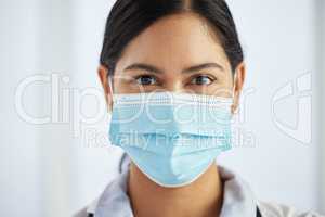 Trust me with your health. a doctor wearing a face mask and standing alone in her clinic during the day.