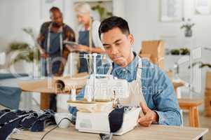 Tailor stitching and making clothes with sewing machine in fashion, design and creative workshop. Serious man working on handmade, trendy and stylish clothing for fashionable boutique or store