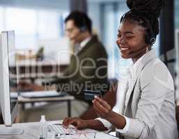 Ready to spoil myself. a young female call center agent holding a credit card at work.