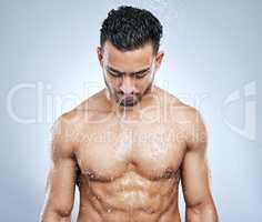 Refresh your senses. Studio shot of a handsome young man taking a shower against a grey background.