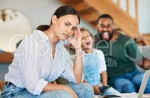 All this noise is becoming really irritating. Portrait of a mother looking stressed out while her daughter and husband are screaming in the background at home.