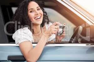 Dont just make memories, capture them. a young woman hold a camera while out on a road trip.