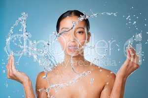 Moisture is your best friend for skincare. an attractive young woman posing against a blue background in the studio and splashing her face with water.