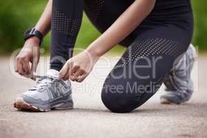 I wont fall or fail on my goals. Closeup shot of an unrecognisable woman tying her shoelaces while exercising outdoors.