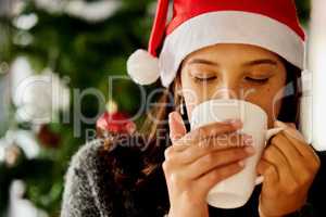 Christmas is not a time nor a season, but a state of mind. a young woman drinking coffee at home.