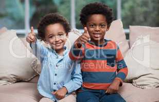 Brothers are the best. Portrait of two little boys showing thumbs up at home.