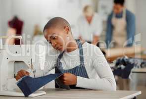 Fashion, design and creative work at a workshop. Young african American factory worker sewing new, trendy, fashionable clothing of the season. Black female working on a machine in a busy workplace