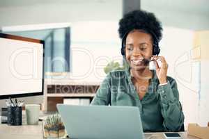 Let me log into your account from my side... a young businesswoman wearing a headset while working on a laptop in an office.