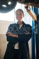 Money cant buy happiness but it can buy a good mechanic. a female mechanic posing with her arms crossed in an auto repair shop.