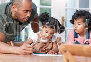 Getting creative is tons of fun. a father colouring in a picture with his two little daughters at home.