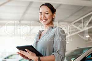Be sure to make the right choice. a woman using her digital tablet in a car dealership.
