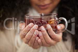 This drink cures all. an unrecognizable young woman drinking a glass of herbal tea while sitting on a sofa at home.