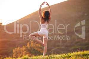 A beautiful place to find your zen. Rearview shot of an unrecognizable young woman practicing yoga outside on a sunny morning.