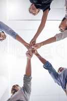We can do this together. a group of businesspeople joining their fists together in unity at work.
