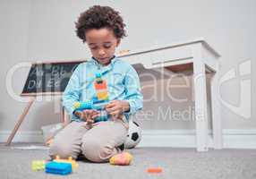 Guess what Im building... a young boy playing with building blocks in a room.