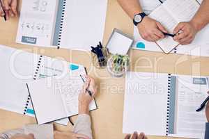 Information is key in achieving success. High angle shot of a group of unrecognizable businesspeople looking over paperwork while sitting around a table in the boardroom.