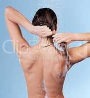 Hair growth flourishes from a clean, healthy scalp. Studio shot of a young woman rinsing her hair while taking a shower against a blue background.