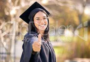Certified goal getter. a young woman showing thumbs up on graduation day.