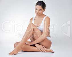 Your skin requires immense hydration. a young woman sitting on the floor against a studio background.