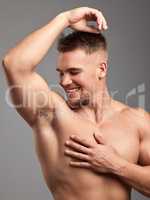 How you doin. Studio shot of a handsome young man smelling his armpit against a grey background.