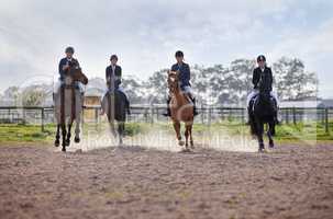 Its a race to the finish. Full length shot of a group of attractive young female jockeys riding their horses out on the farm.