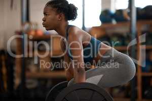 Born to be buff. an attractive and athletic young woman working out with a barbell in the gym.