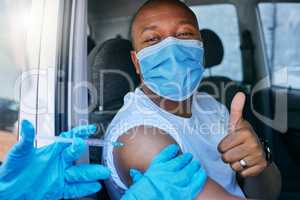 Drive thru covid and corona virus vaccine site as a public service for the people. Man giving thumbs up and endorsing the jab while wearing a mask to avoid infection, approving being vaccinated