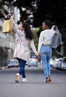 Making our way downtown. two friends cheerfully walking down the street after spending the day shopping.