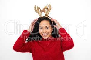 Im just here to spread some Christmas cheer. Studio shot of a young woman wearing a reindeer antlers headband against a white background.