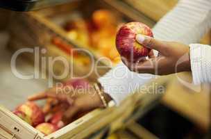 Treat your body like a sanctuary. a woman surveying the apples in a grocery store.