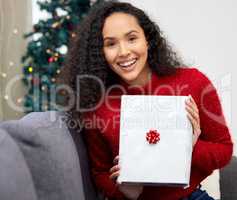 The best way to spread Christmas cheer is singing loud for all to hear. a young woman opening presents during Christmas at home.