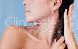 To smell like a flower, take a shower. Studio shot of an unrecognisable woman rinsing her hair while taking a shower against a blue background.